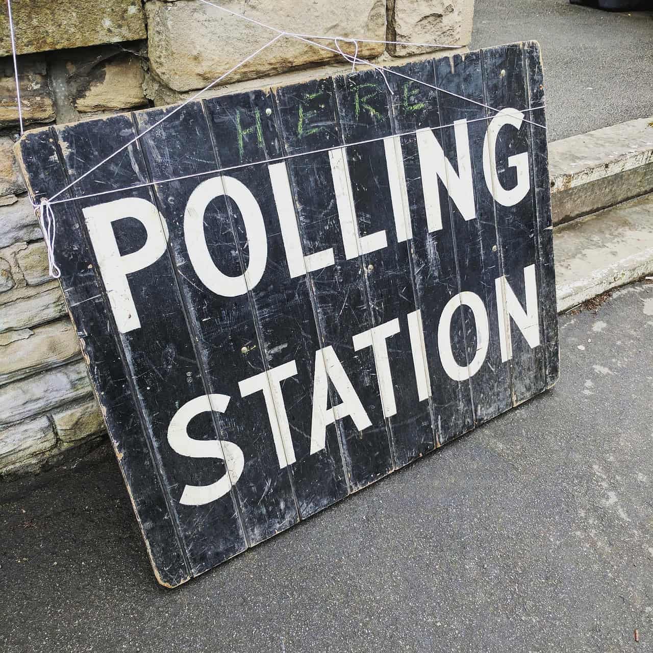 Polling station sign on a sidewalk for voting during elections.