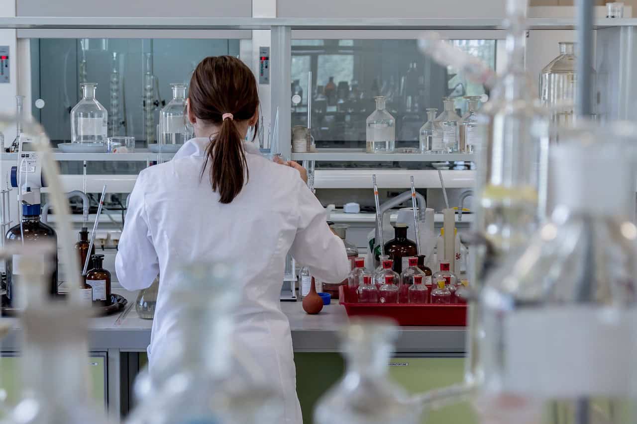 Scientist working in a laboratory with glassware and chemicals.